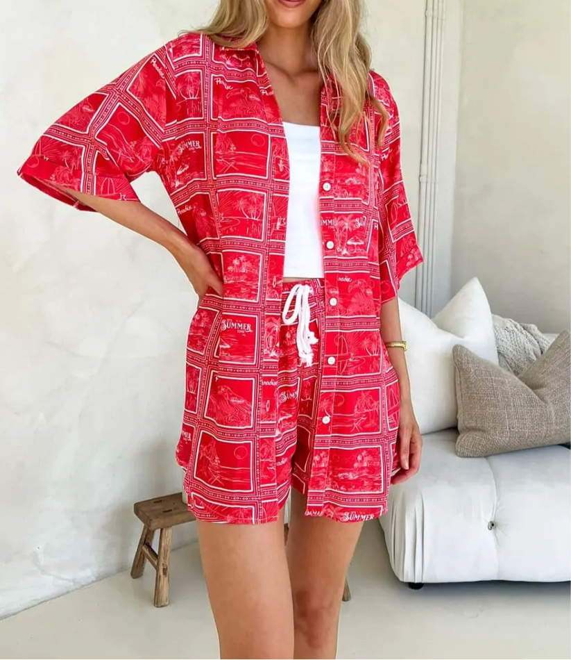Posing model wearing Summer Set – matching red printed shirt and shorts with white drawstring waist and bold tropical holiday print