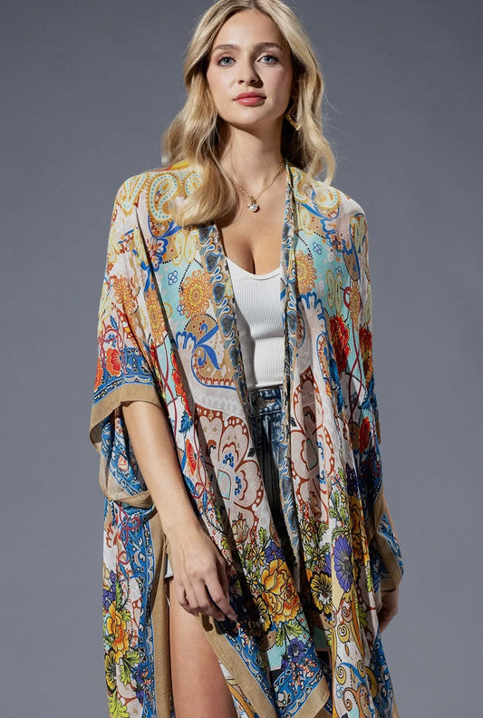 Boho floral kimono for women featuring an intricate multicolour paisley and floral print with blue, orange, and yellow tones. Lightweight and flowy, styled with denim shorts and heels – perfect as a beach kimono or casual layering piece. Close up.