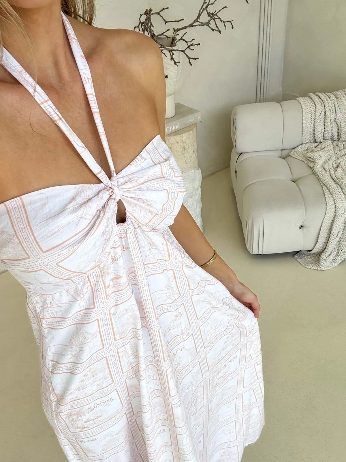 Close up of white printed halter neck dress with front knot detail, lightweight cotton midi dress for summer