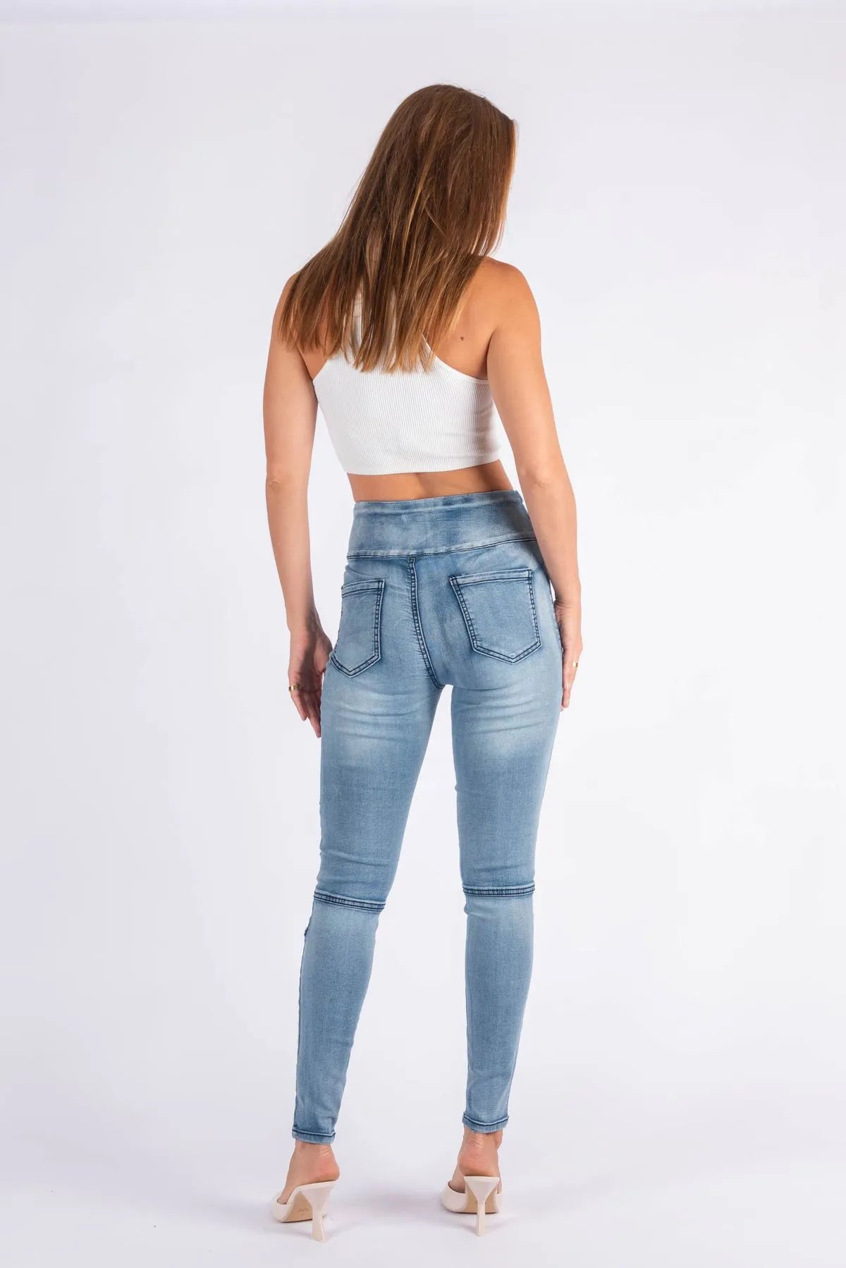 Back View pair of high-waisted skinny jeans with ribbed moto paneling on the thighs and knees, in a light wash with subtle fading.