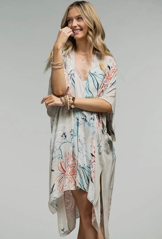 Woman wearing the Rumi kimono – lightweight boho kimono with pastel floral print, styled with a lace cami and black shorts.