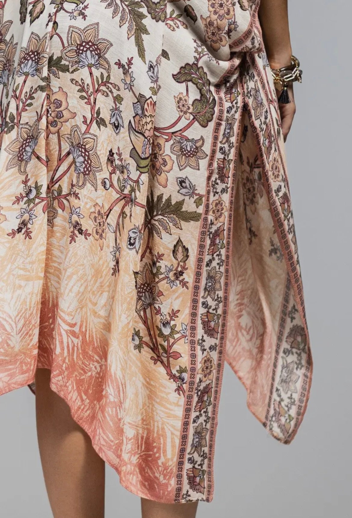 Woman wearing a boho floral kimono with wide sleeves and open front, layered over a white tank and black shorts pattern close up